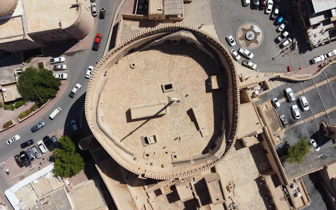 Aerial view of Nizwa Fort's circular courtyard and surrounding streets in Oman.