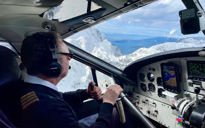 Pilot navigating seaplane over glaciers and volcanic formations on Whistler Glacier tour.
