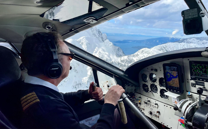 Pilot navigating seaplane over glaciers and volcanic formations on Whistler Glacier tour.