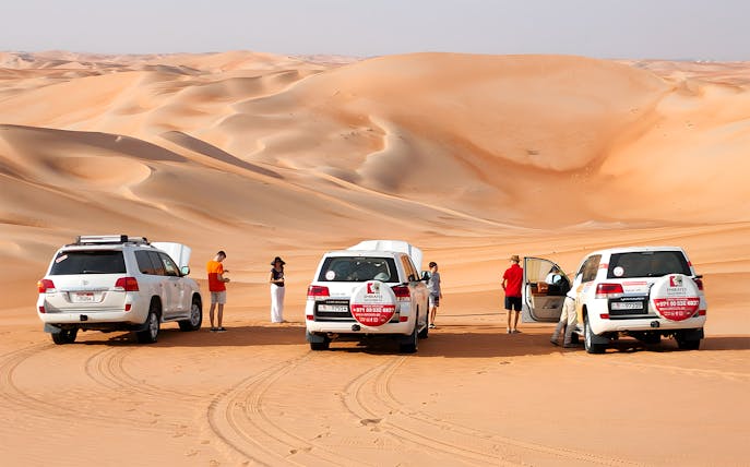 Desert drive tour with SUVs and tourists at Liwa Oasis, Abu Dhabi.