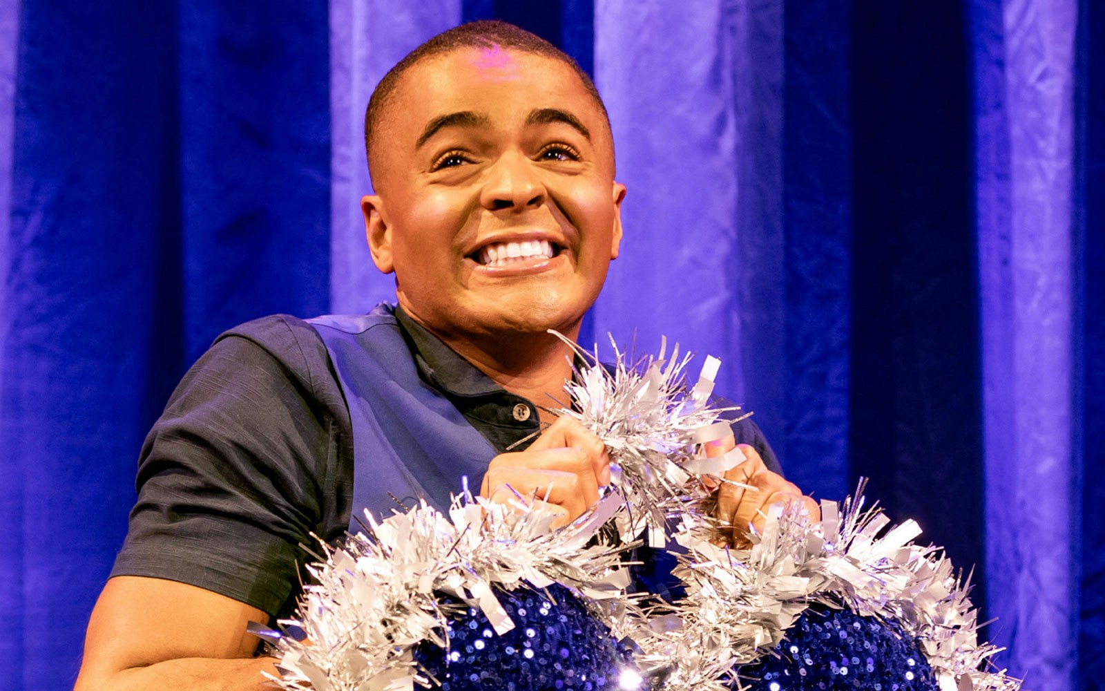 Performer smiling with silver tinsel in Titanique show.