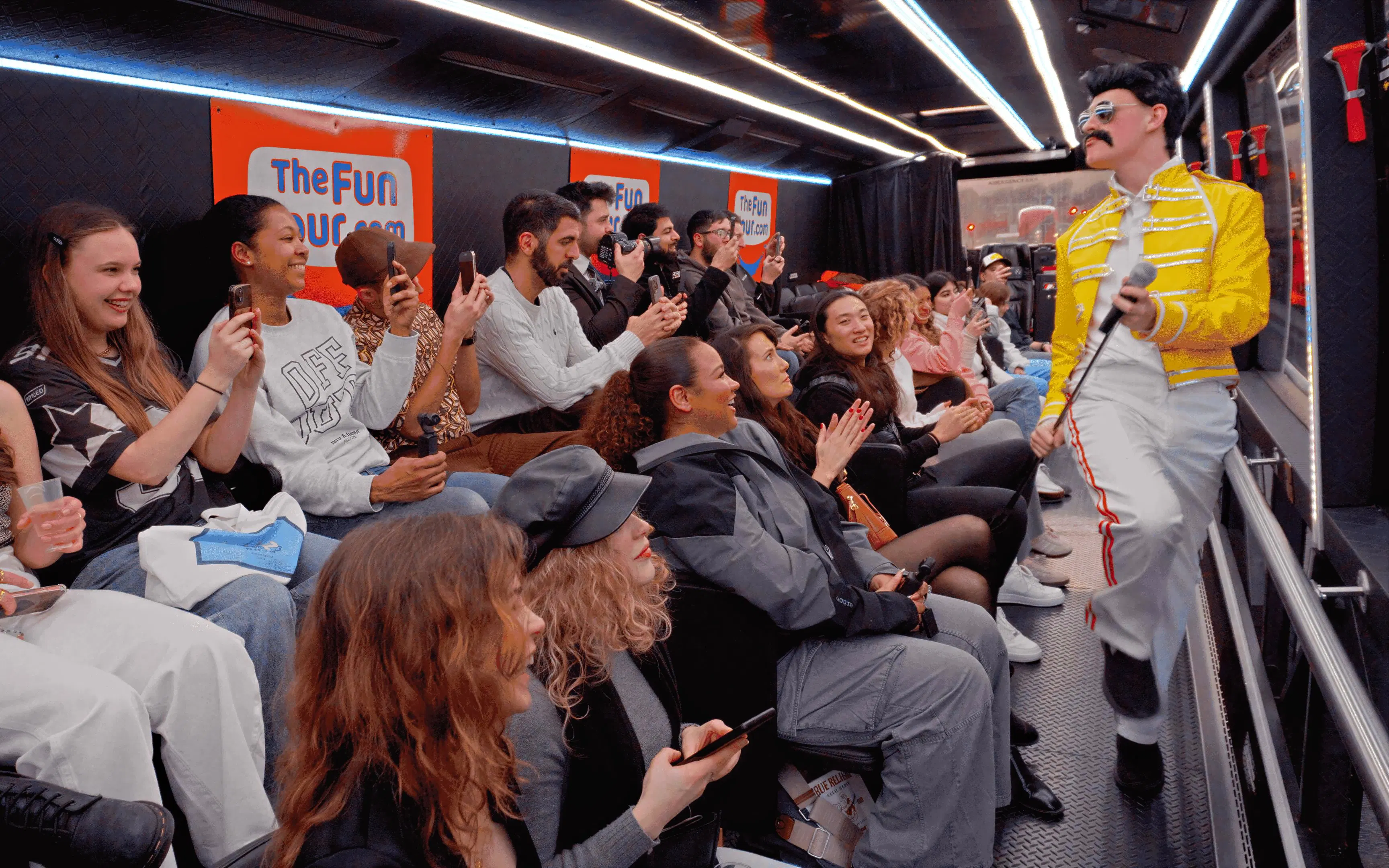 Tour group enjoying live performance on a bus with a performer in a yellow jacket.
