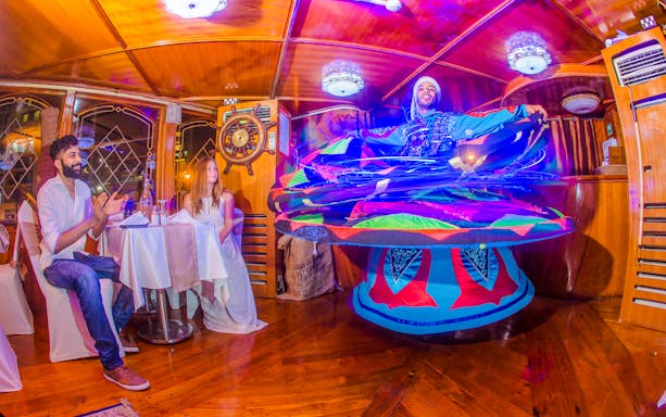 Tanoura dancer performing on Alexandra VIP Dhow Cruise with guests watching.