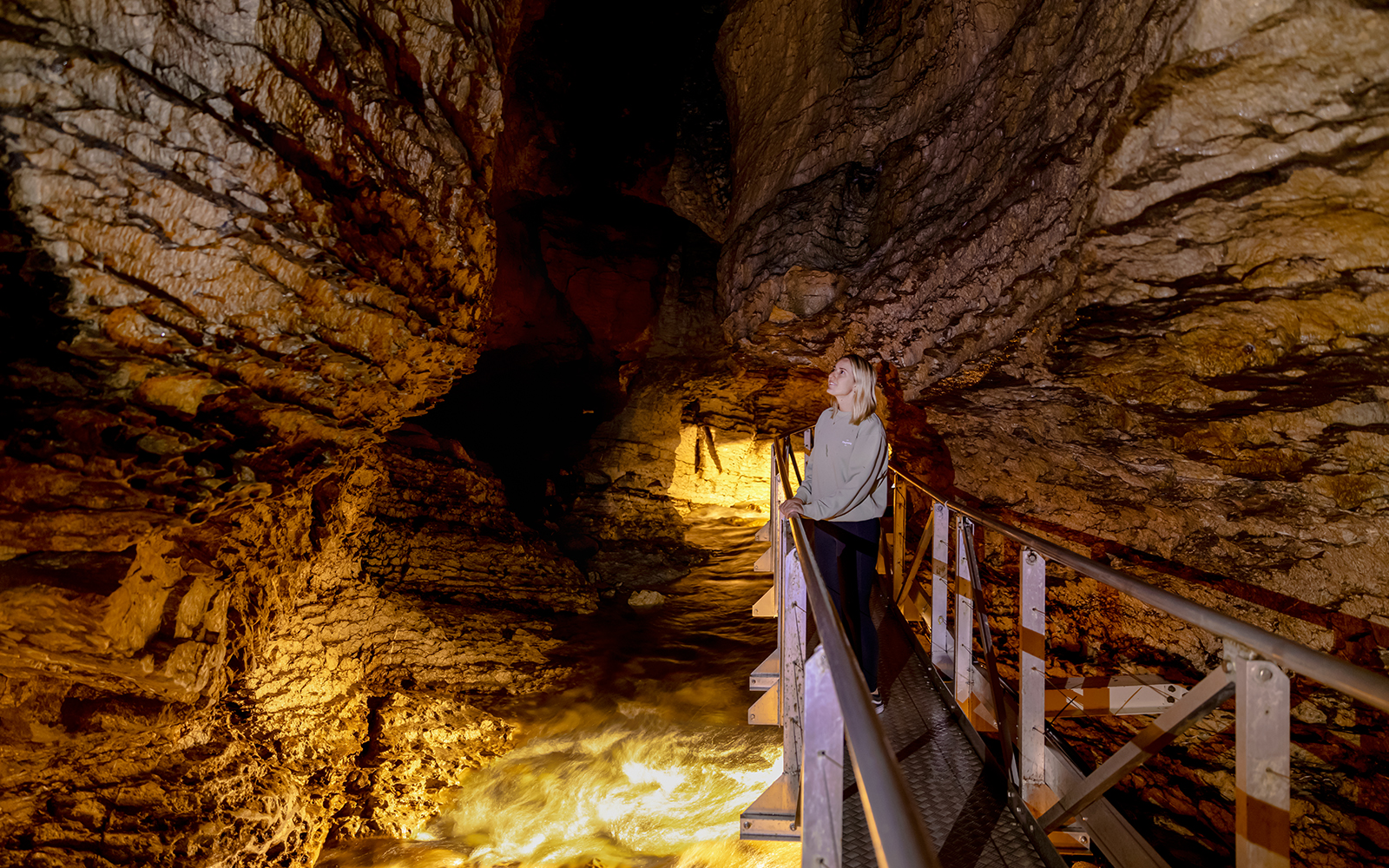 Tourist exploring Te Anau Glowworm Caves on a walkway.