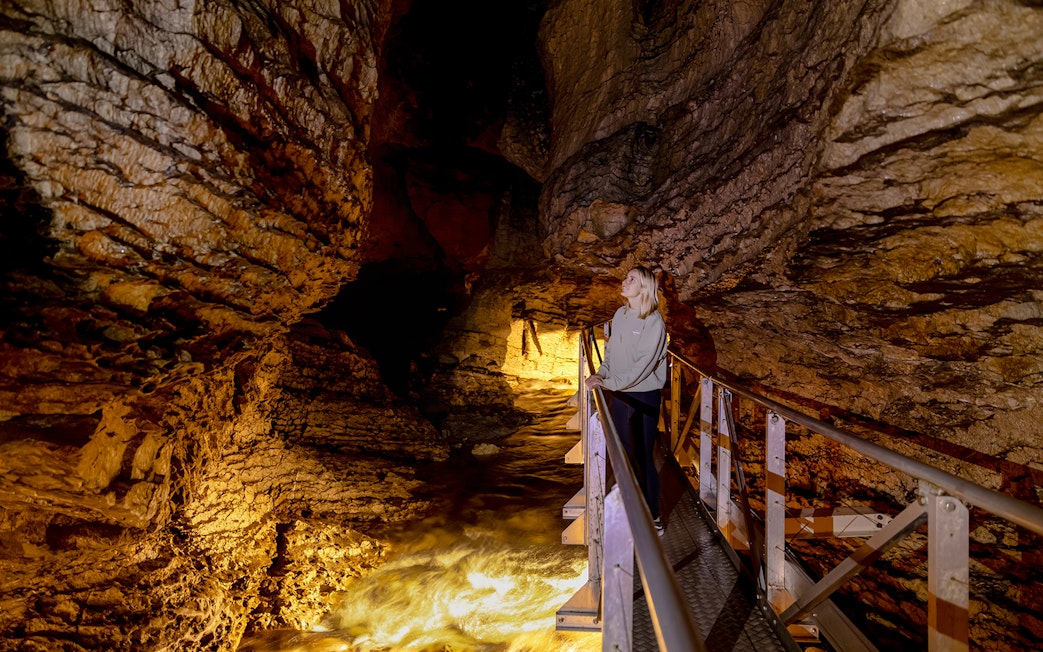 Tourist exploring Te Anau Glowworm Caves on a walkway.