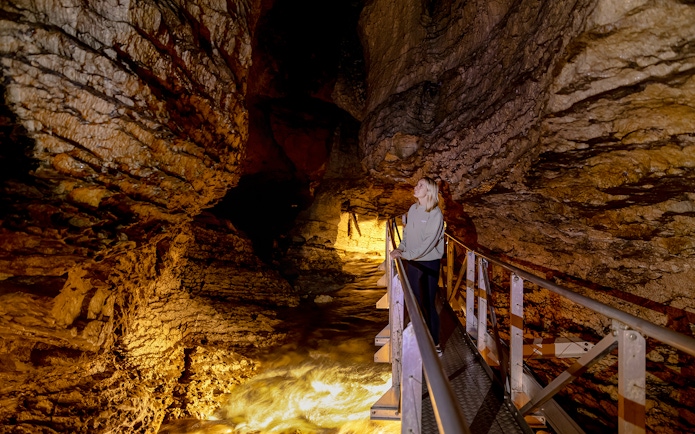 Tourist exploring Te Anau Glowworm Caves on a walkway.