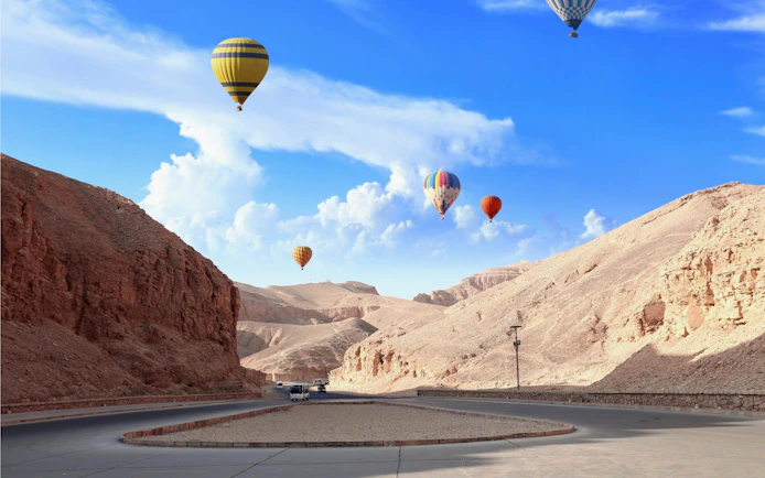 Hot air balloons over the Valley of Kings, Luxor, Egypt, with desert landscape.