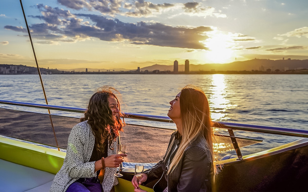 Tourists enjoying sunset aboard a catamaran cruise in Barcelona.