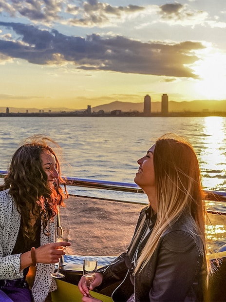 Tourists enjoying sunset aboard a catamaran cruise in Barcelona.