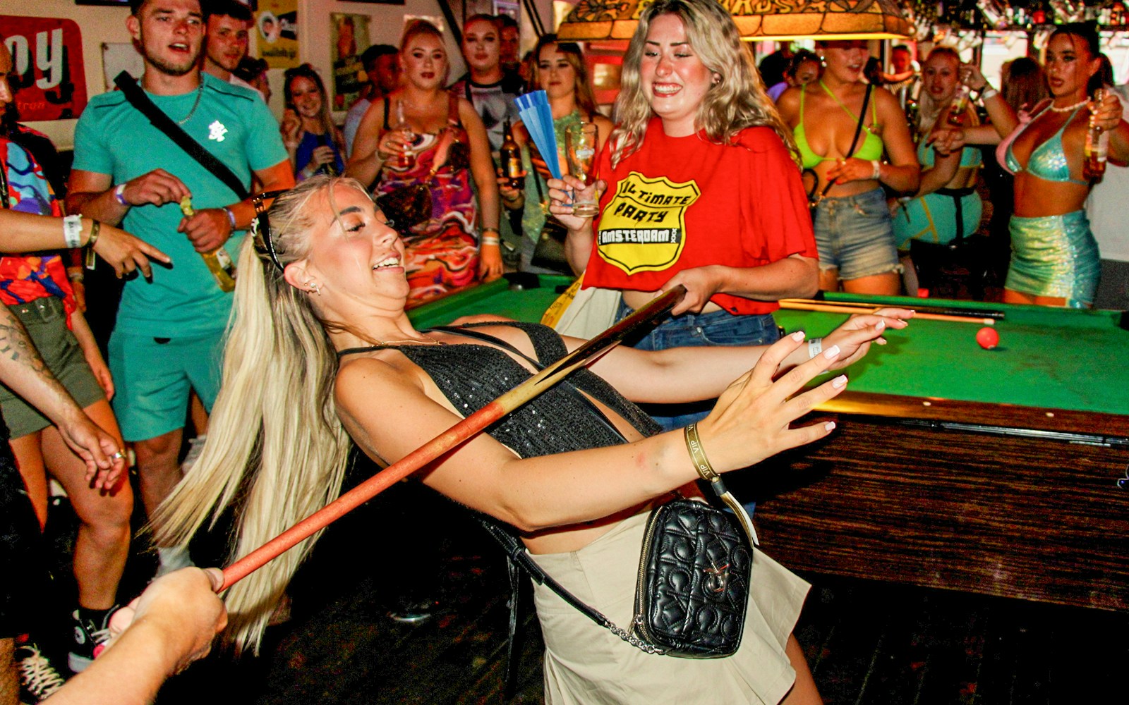 Partygoers enjoying a limbo game during an Amsterdam Red Light District pub crawl.