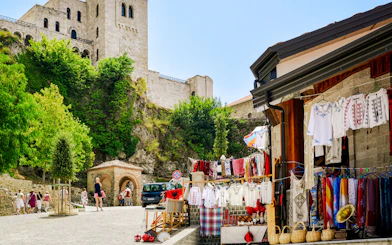 Market stalls with traditional clothing near Kruje Castle, Albania, with tourists exploring the area.
