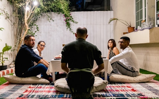 Guests seated around a table for Chef Kuv's Secret Supper, an underground dining experience.