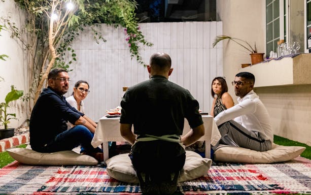 Guests seated around a table for Chef Kuv's Secret Supper, an underground dining experience.