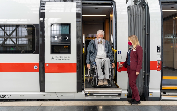 Man in wheelchair assisted onto train by staff, Interrail Germany Mobile Pass.