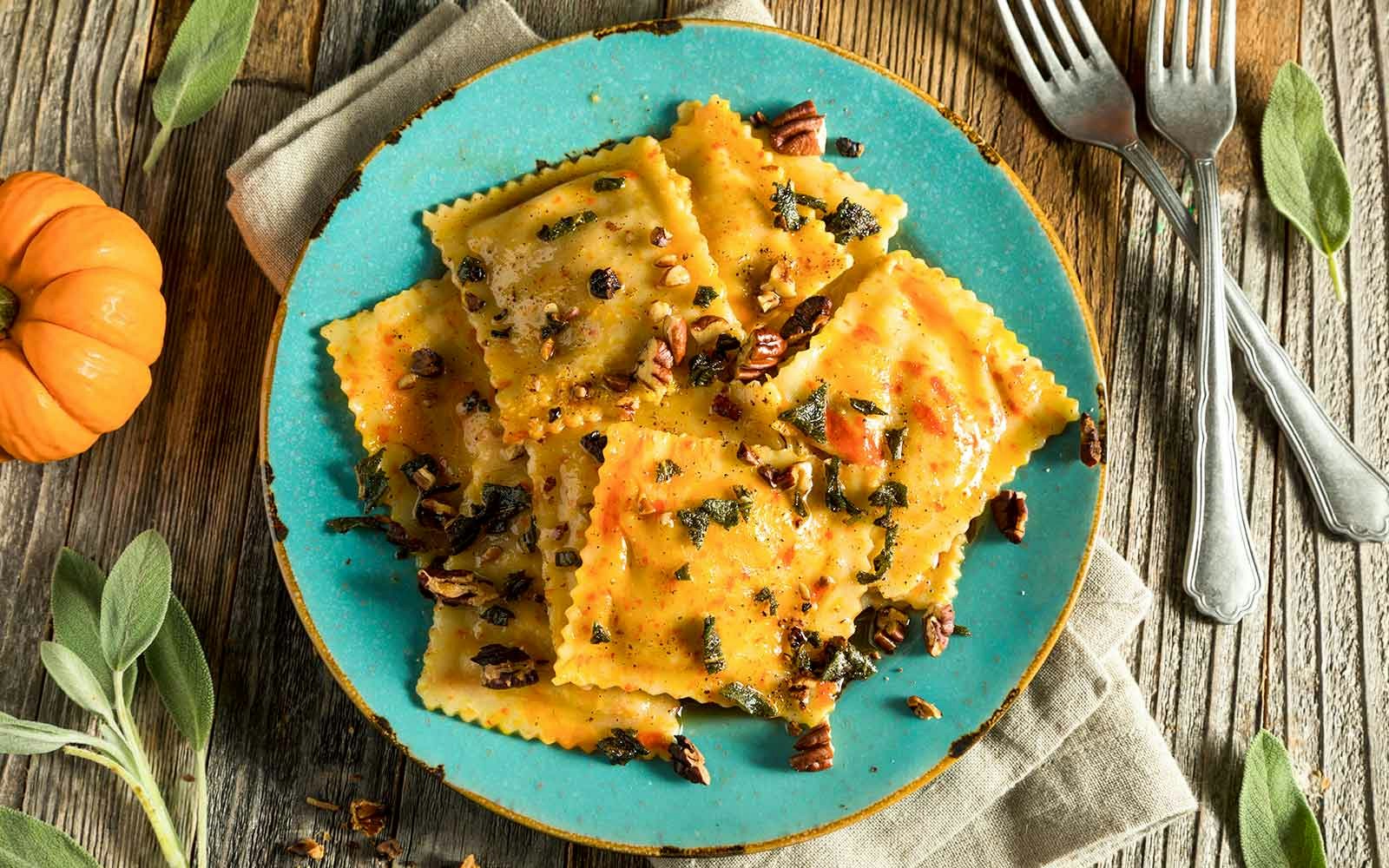 Pumpkin ravioli served on a white plate with a garnish of fresh herbs.