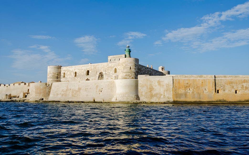 Maniace Castle with lighthouse viewed from the sea in Syracuse, Sicily.