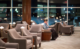 Woman reading in airport lounge with empty chairs around.