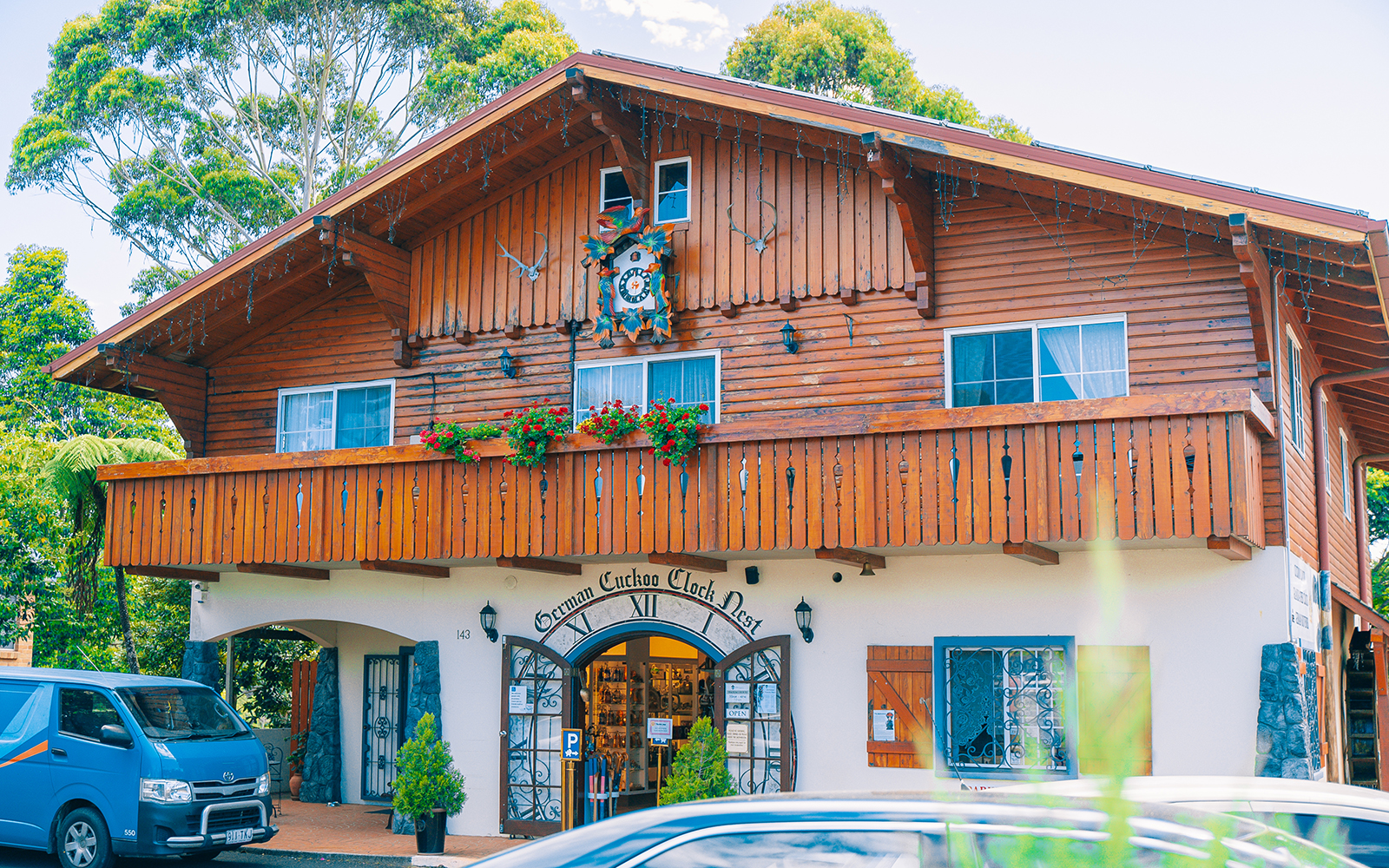 German Cuckoo Clock Nest on Tamborine Mountain, showcasing wooden architecture and vibrant flowers.