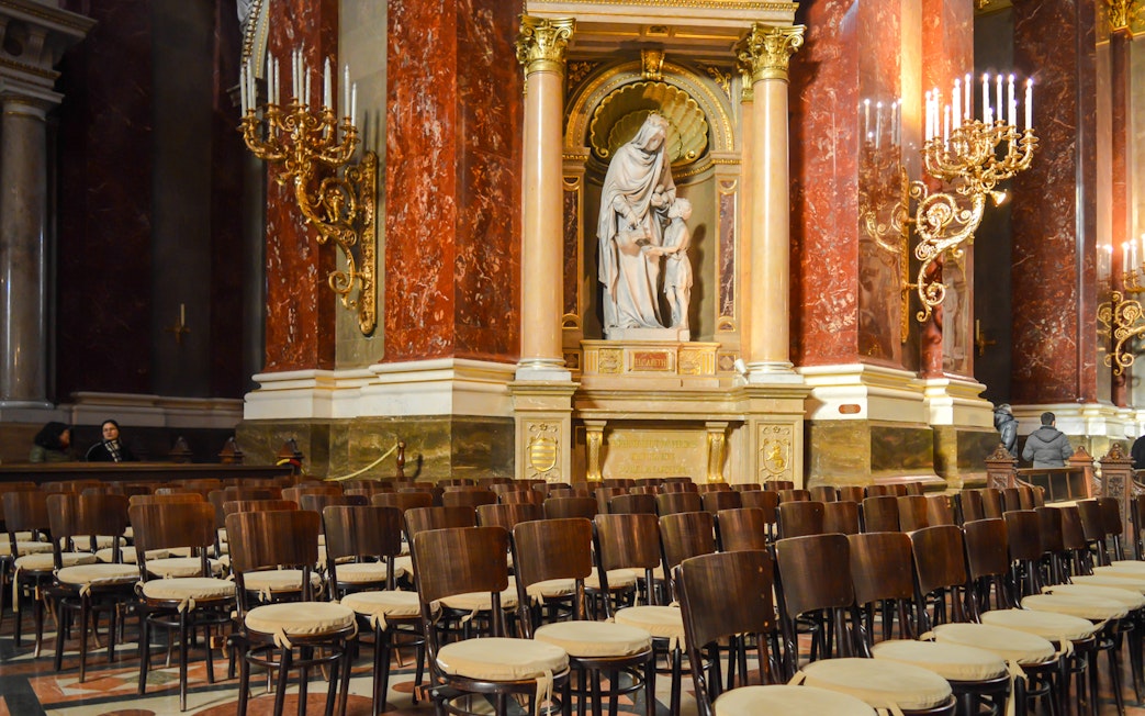 St. Stephen's Basilica interior with statue and ornate chandeliers.