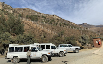 4x4 vehicles at Sani Pass with mountain backdrop on small group tour from Durban.