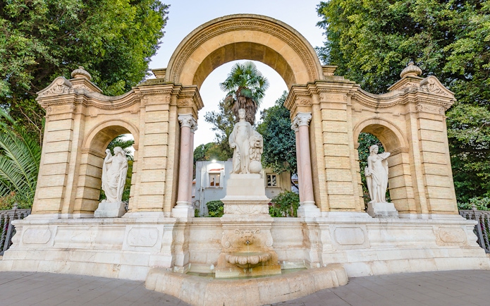Statues and archway in María Luisa Park, Seville, on a guided tour.