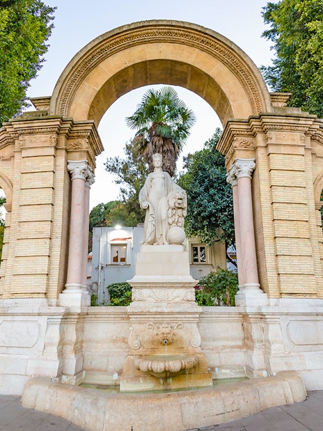 Statues and archway in María Luisa Park, Seville, on a guided tour.