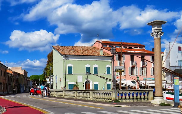 Street view in Cesenatico with colorful buildings near the Maritime Museum and Marino Moretti House.