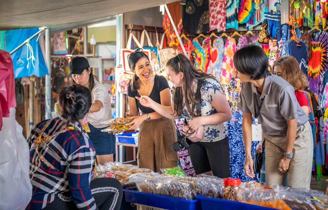 Shoppers interacting with vendors at Maeklong Railway Market, Thailand.