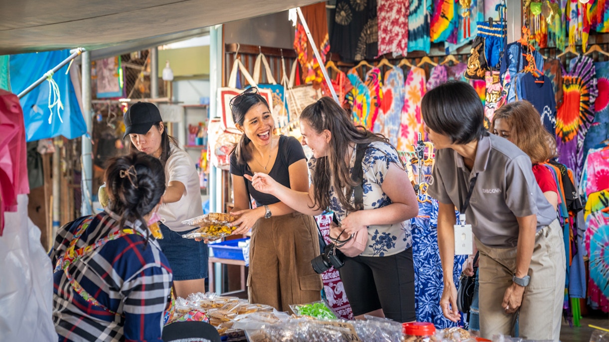 Shoppers interacting with vendors at Maeklong Railway Market, Thailand.