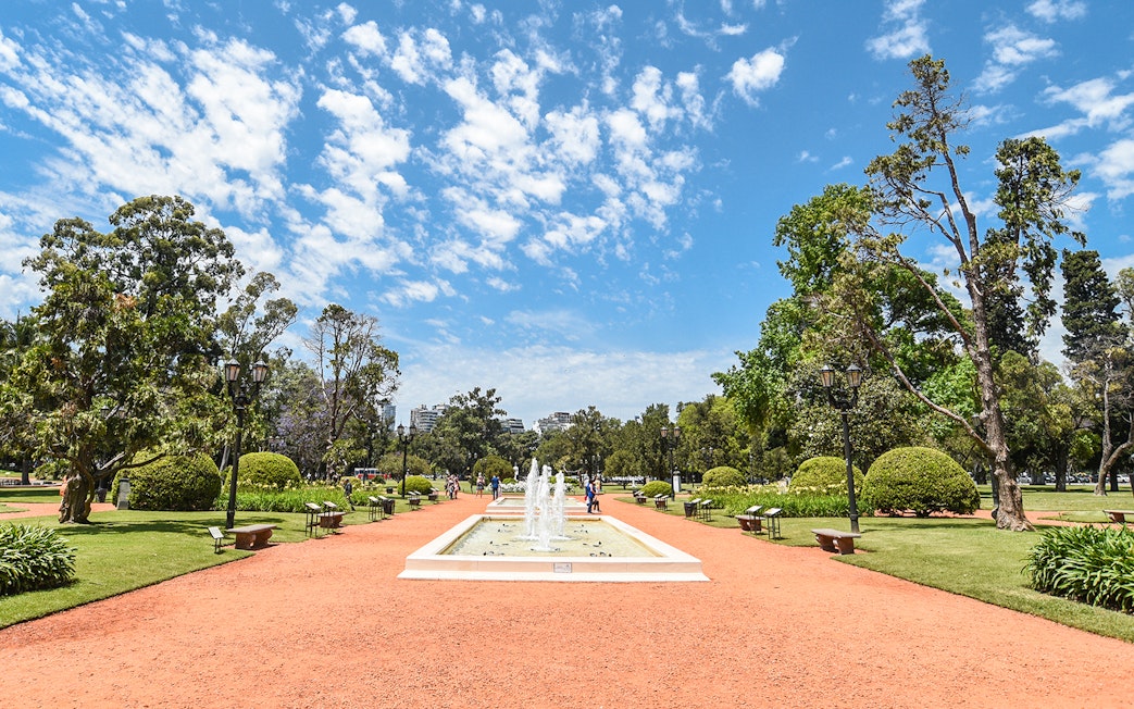 Fountain and pathways in English garden, Palermo, surrounded by trees and benches.