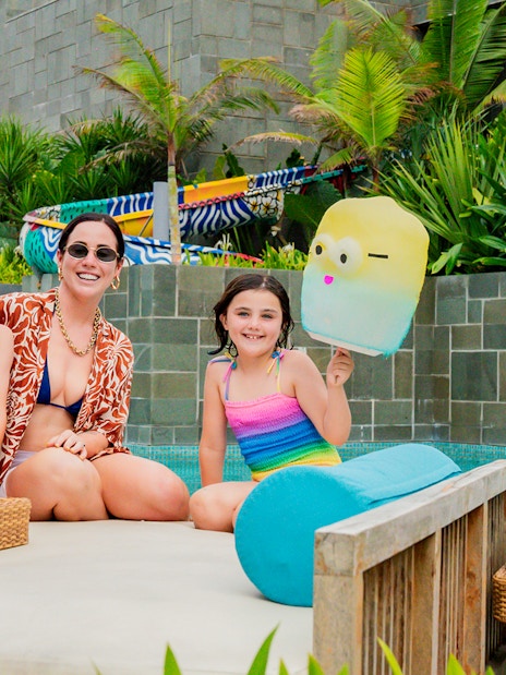 Family enjoying daybeds at Atlas Beach Club, Bali, with colorful pool floats.