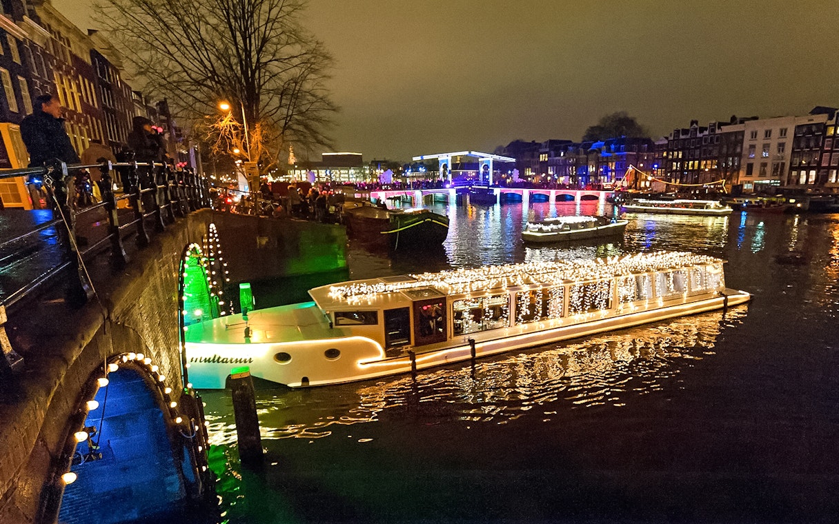 Amsterdam canal with illuminated boat during Light Festival cruise.