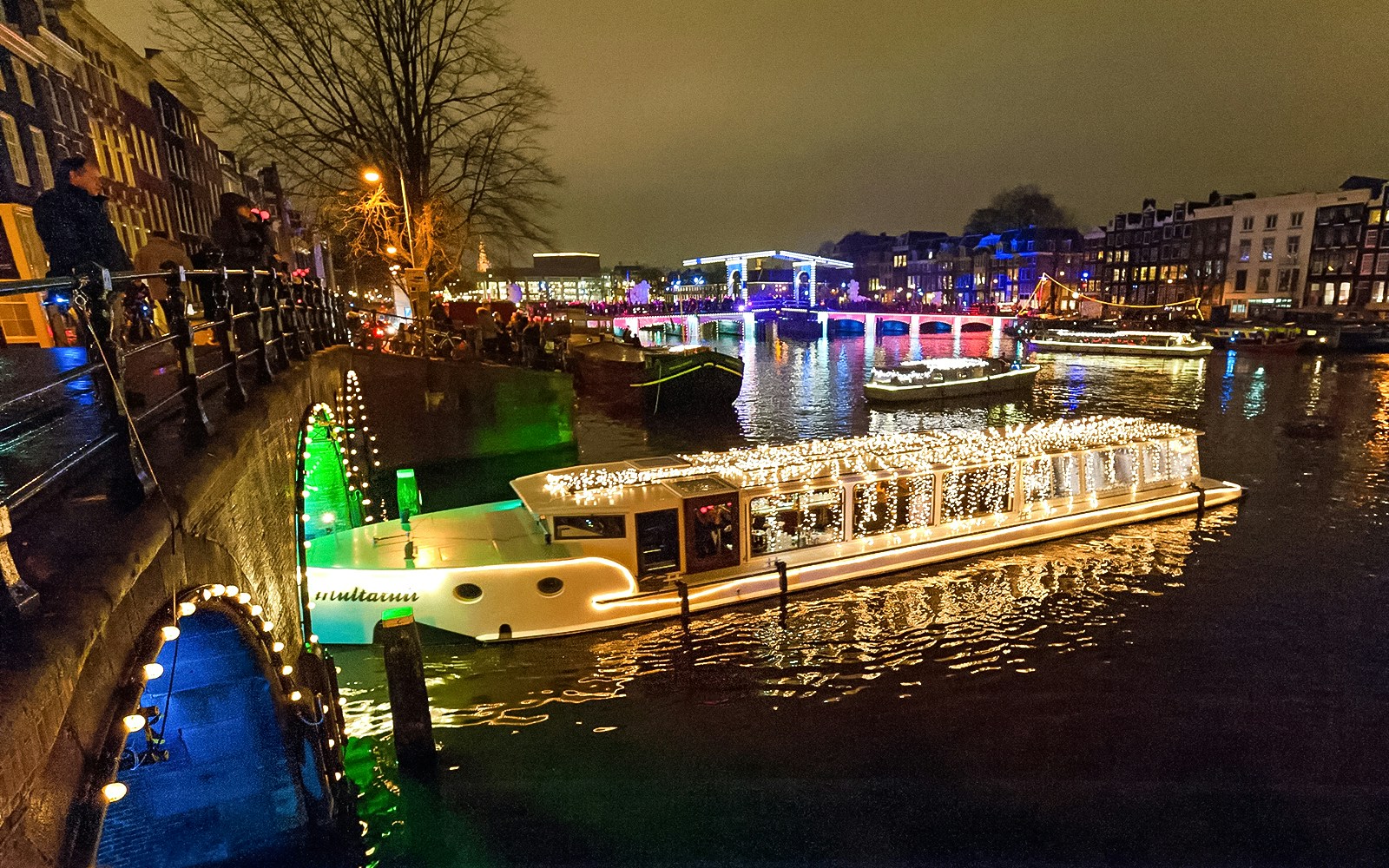 Amsterdam canal with illuminated boat during Light Festival cruise.