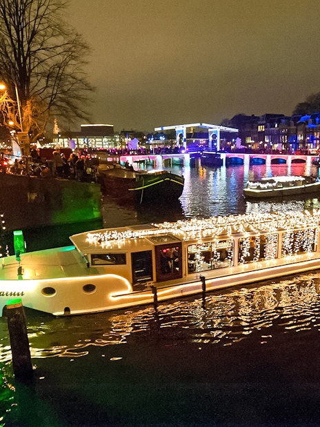 Amsterdam canal with illuminated boat during Light Festival cruise.