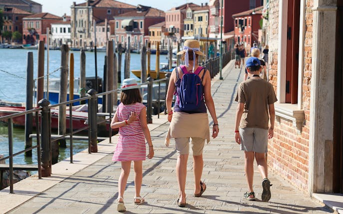 Family walking along a canal in Burano during a guided tour from Punta Sabbioni.