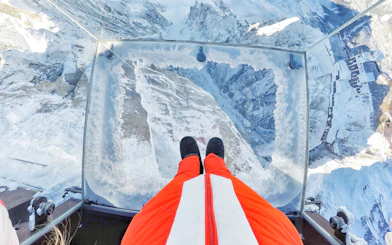 View from a glass platform overlooking snowy Chamonix Mont Blanc during a cable car ride.