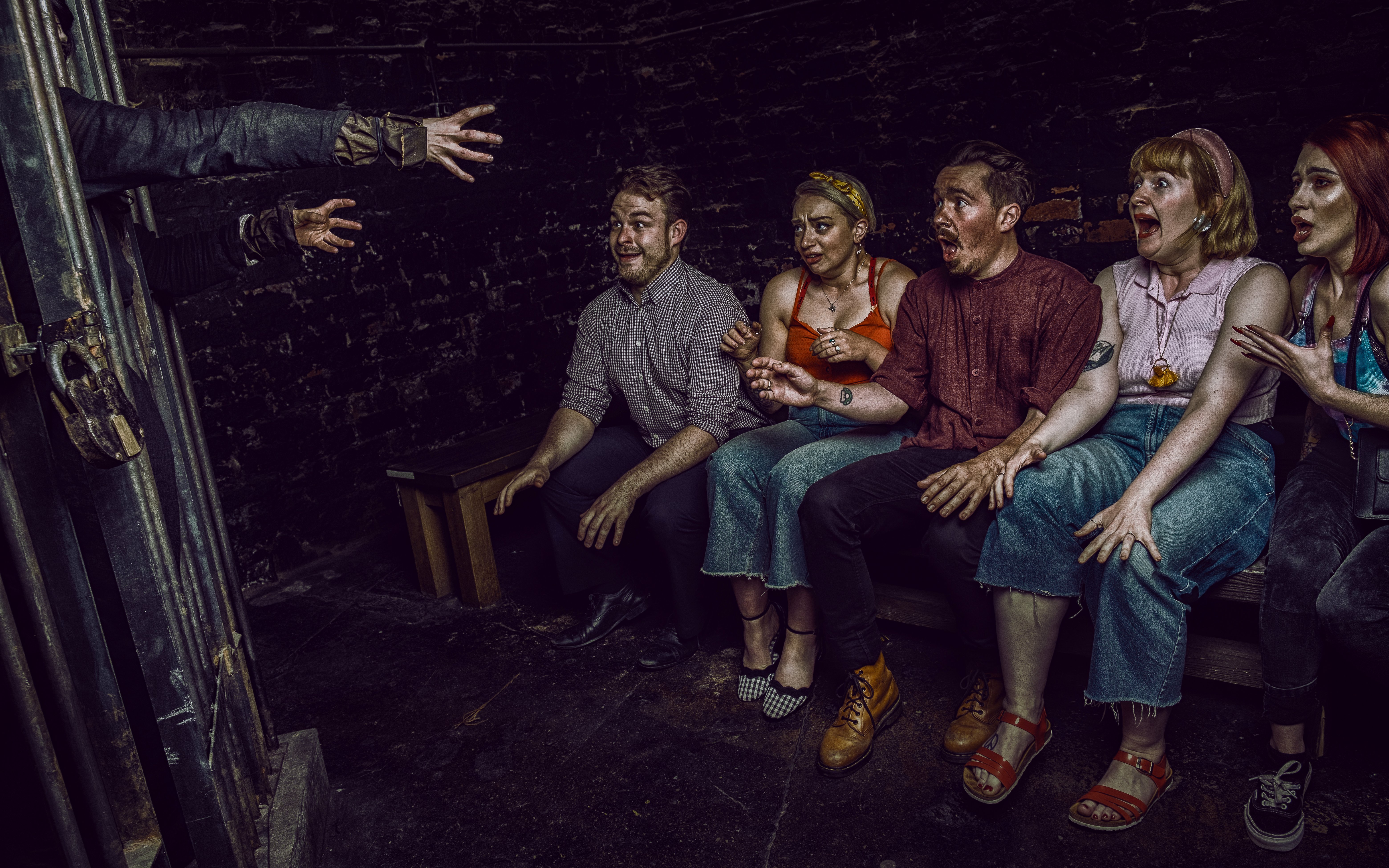 Visitors react to a witch's hands reaching out at York Dungeon's Curse of the Witch experience.