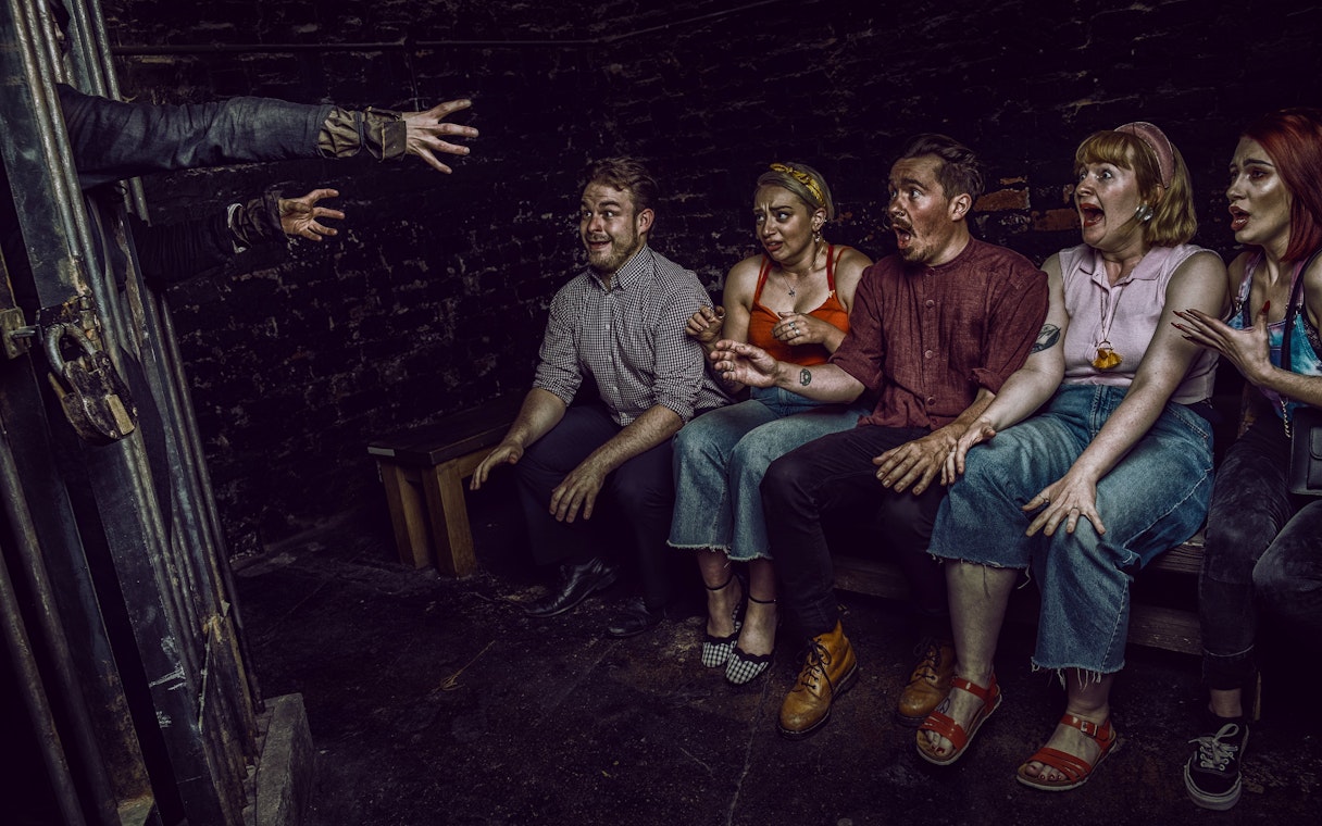 Visitors react to a witch's hands reaching out at York Dungeon's Curse of the Witch experience.
