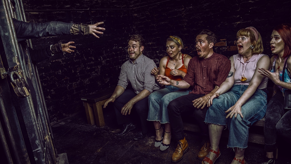 Visitors react to a witch's hands reaching out at York Dungeon's Curse of the Witch experience.