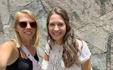 Two people smiling in front of a textured stone wall in Mexico City.