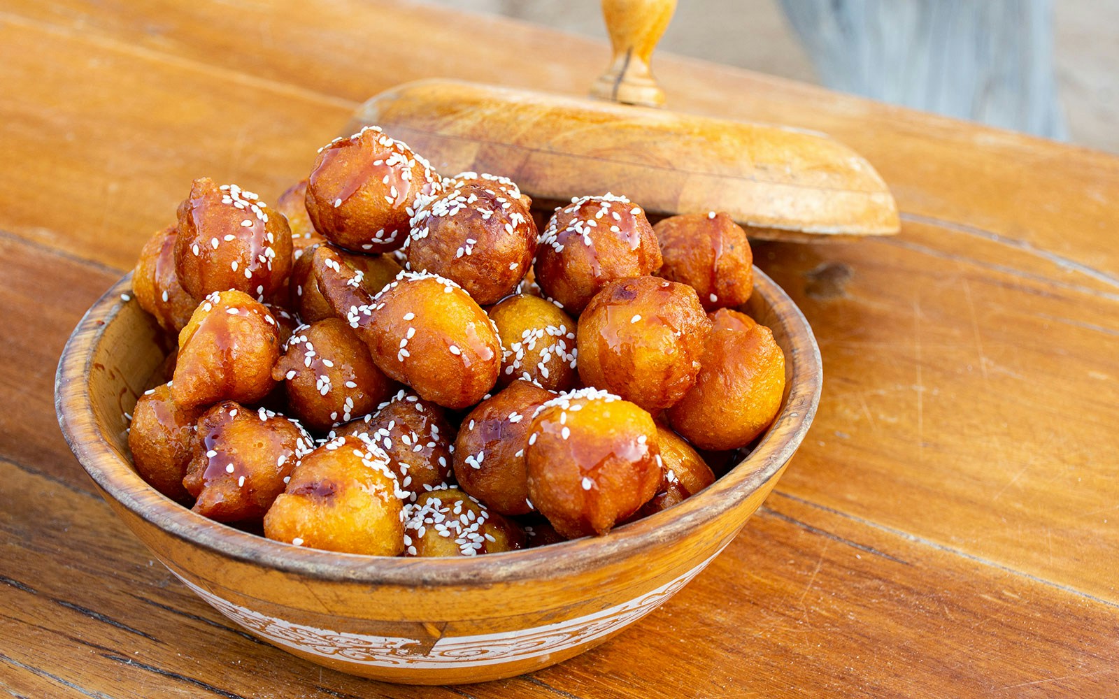 Luqaimat in a wooden bowl with sesame seeds, traditional Emirati dessert in Dubai.