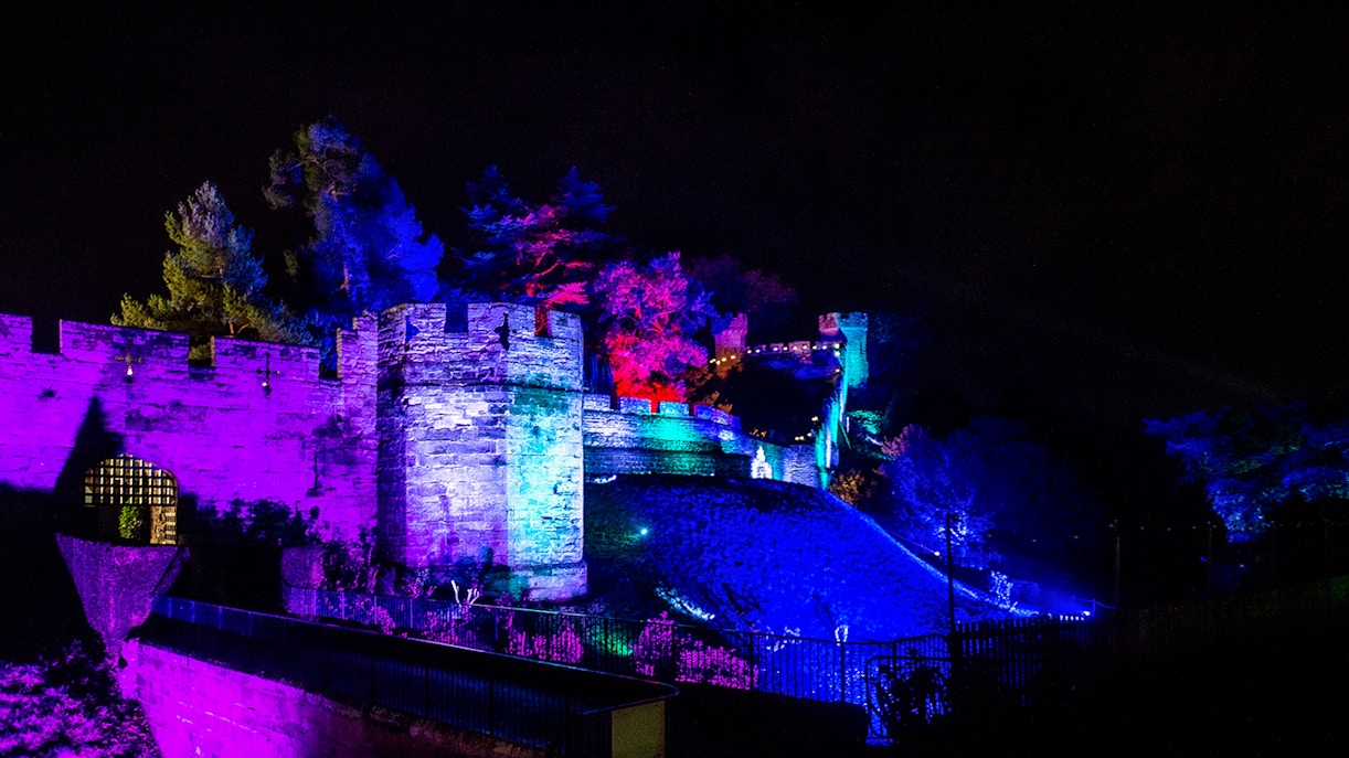 Warwick Castle illuminated in vibrant colors during the Light Trail event.