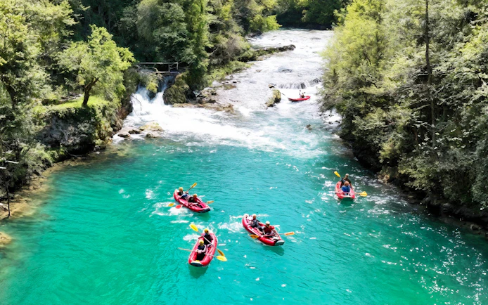 Tourists kayaking on Mrežnica River near waterfalls in Split.