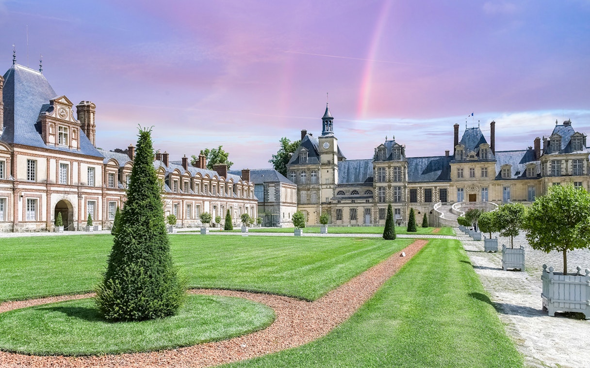 Château de Fontainebleau courtyard with manicured gardens and historic architecture.