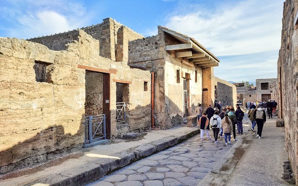 Tour group exploring ancient streets of Pompeii, Naples.