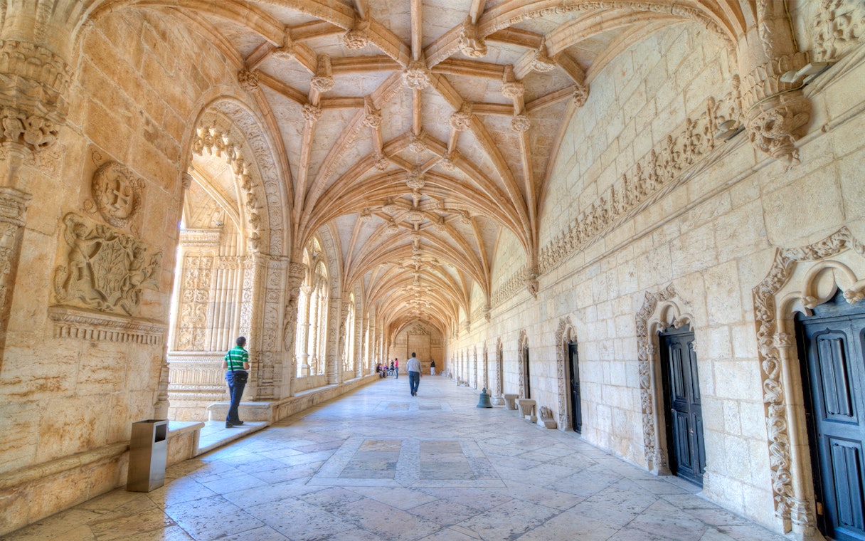 Visitors walking through the ornate corridors of Jeronimos Monastery, Lisbon.