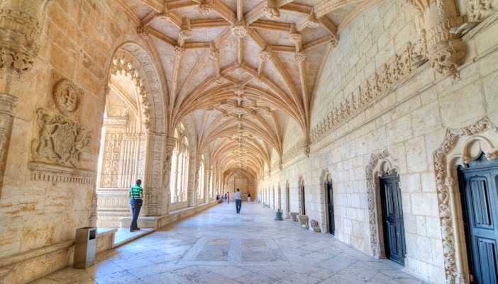 Visitors exploring the ornate corridors of Jeronimos Monastery in Lisbon, Portugal.