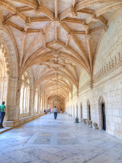 Visitors walking through the ornate corridors of Jeronimos Monastery, Lisbon.