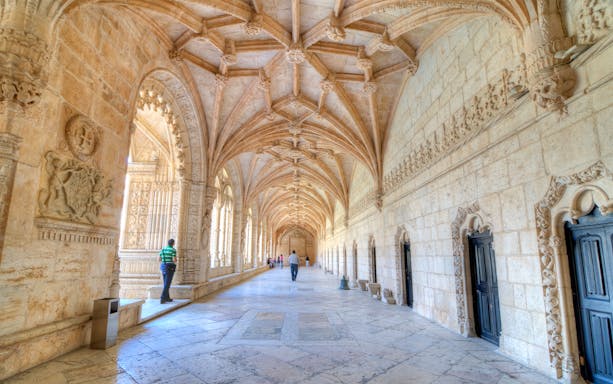 Visitors walking through the ornate corridors of Jeronimos Monastery, Lisbon.
