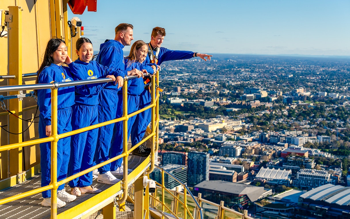 Group on Sydney Tower Eye Skywalk overlooking cityscape.